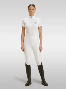 Rider wearing white Elite Competition riding breeches with a white Diamont Equestrian show shirt and tall riding boots, full body
