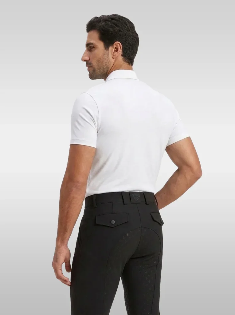 Back three-quarter view of the white Cavalier men’s polo shirt worn with black riding breeches