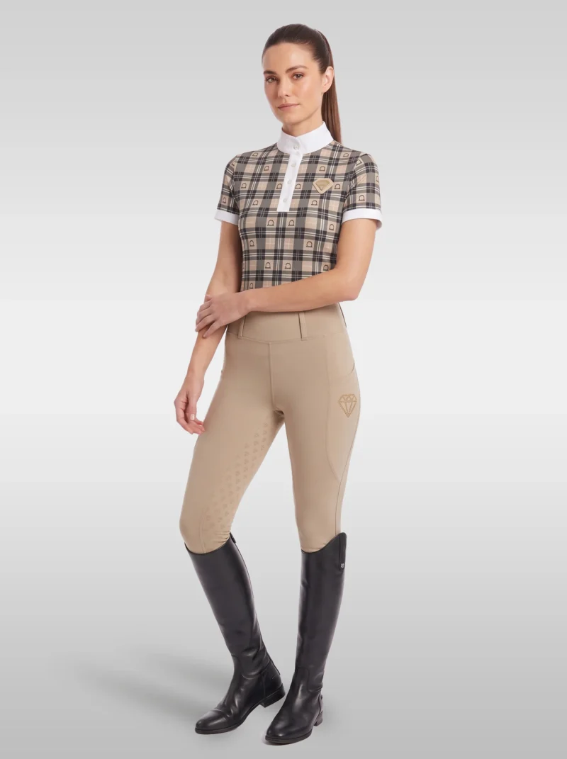 Rider wearing the beige Heritage check base layer with beige riding breeches and tall black riding boots, full body