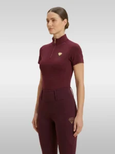 Burgundy Prestige base layer by Diamont Equestrian with gold quarter-zip and gold metal diamond badge on the chest, front three-quarter view