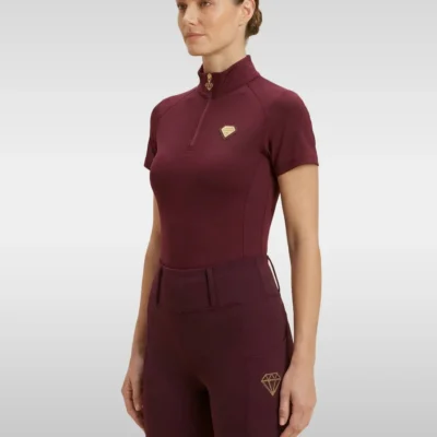 Burgundy Prestige base layer by Diamont Equestrian with gold quarter-zip and gold metal diamond badge on the chest, front three-quarter view