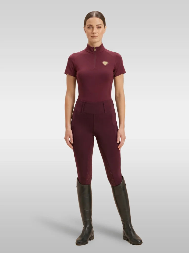 Rider wearing the burgundy Prestige base layer with matching burgundy riding leggings and tall riding boots, full body