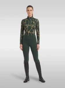 Rider wearing the green Signature long sleeve base layer with matching green riding leggings and tall black riding boots, full body