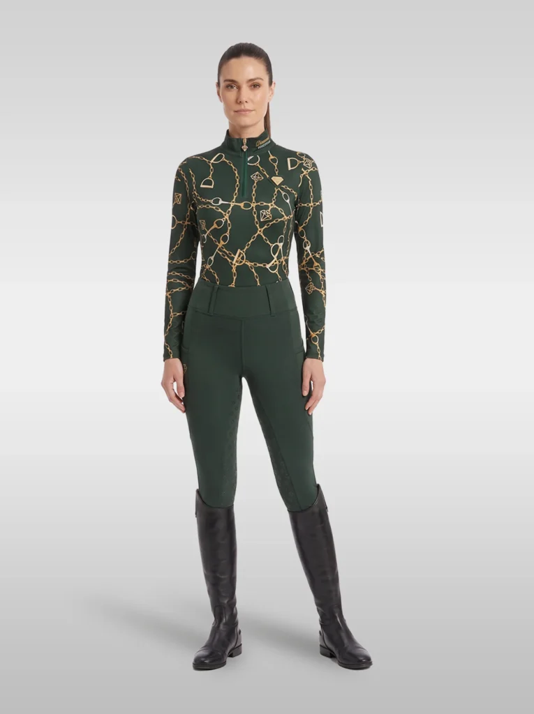 Rider wearing the green Signature long sleeve base layer with matching green riding leggings and tall black riding boots, full body