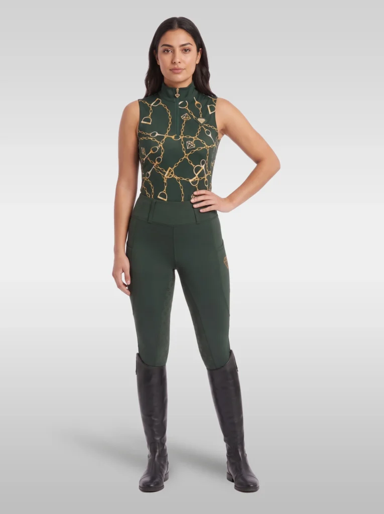 Rider wearing the green Signature sleeveless base layer with matching green riding leggings and tall black riding boots, full body