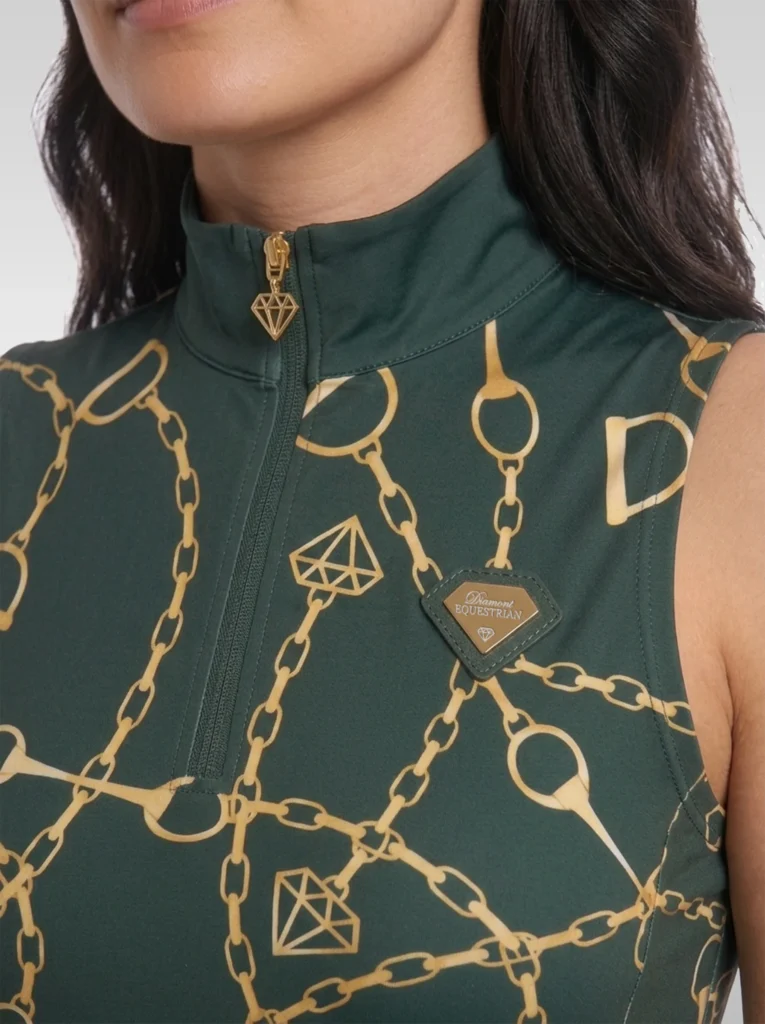Close-up of the green Signature sleeveless base layer: stand-up collar, quarter-zip with gold diamond pull, chain and stirrup print and gold metal diamond badge