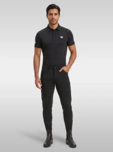 Rider wearing the black Cavalier men’s equestrian polo shirt with black riding breeches and black riding boots, full body