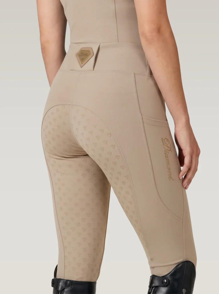 Back three-quarter view of beige equestrian leggings with full-seat diamond grip, waistband badge and Diamont script