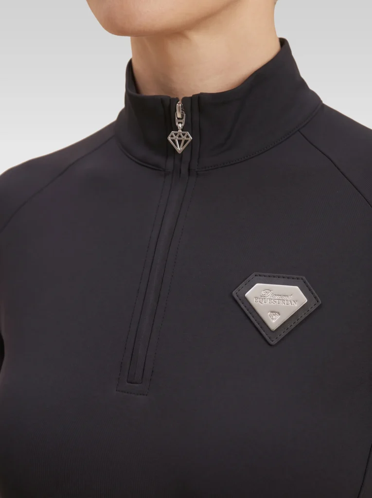 Close-up of the black Prestige base layer: silver zip with diamond pull and silver metal Diamont Equestrian badge in a black leather frame