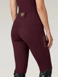 Back three-quarter view of burgundy equestrian leggings with full-seat diamond grip, waistband badge and Diamont script