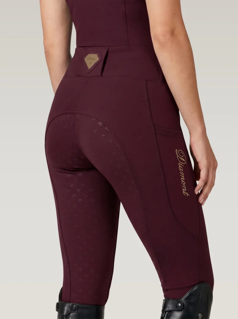 Back three-quarter view of burgundy equestrian leggings with full-seat diamond grip, waistband badge and Diamont script