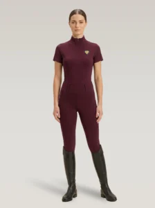 Rider wearing burgundy Prestige riding leggings with a matching Diamont Equestrian base layer and tall riding boots, full body