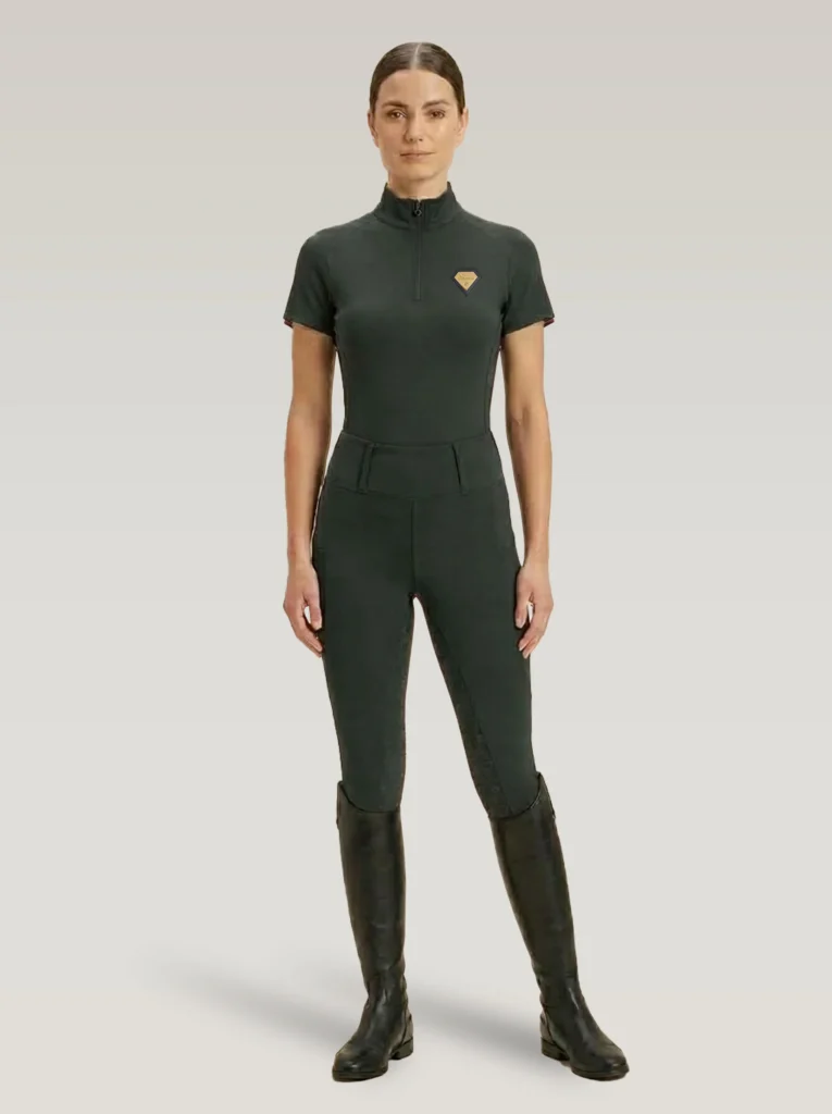 Rider wearing green Prestige riding leggings with a matching Diamont Equestrian base layer and tall riding boots, full body