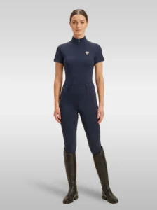 Rider wearing the navy Prestige base layer with matching navy riding leggings and tall riding boots, full body