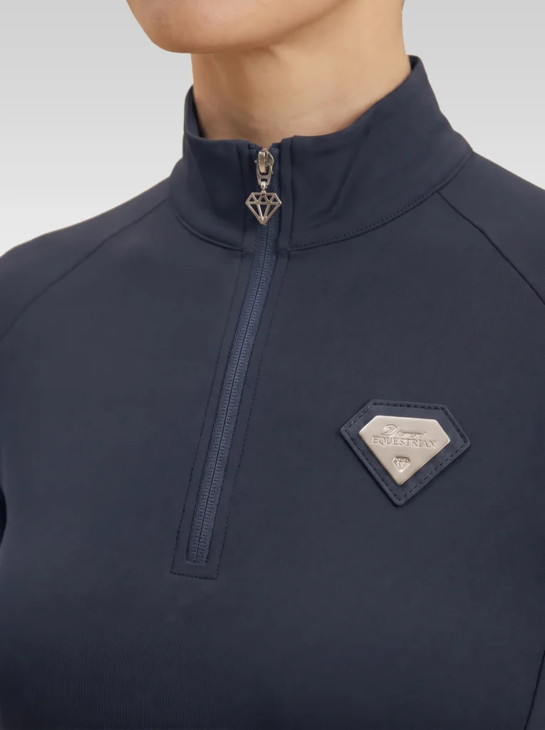 Close-up of the navy Prestige base layer: silver zip with diamond pull and silver metal Diamont Equestrian badge in a navy leather frame