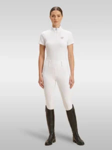 Rider wearing the white Prestige base layer with white riding breeches and tall riding boots, full body