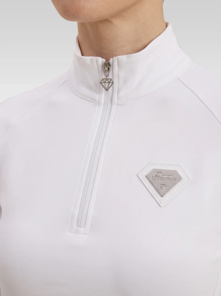Close-up of the white Prestige base layer: silver zip with diamond pull and silver metal Diamont Equestrian badge in a white leather frame