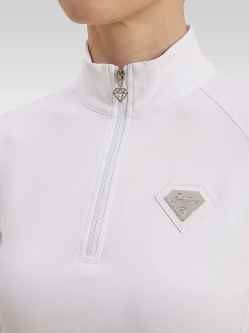 Close-up of the white Prestige base layer: silver zip with diamond pull and silver metal Diamont Equestrian badge in a white leather frame