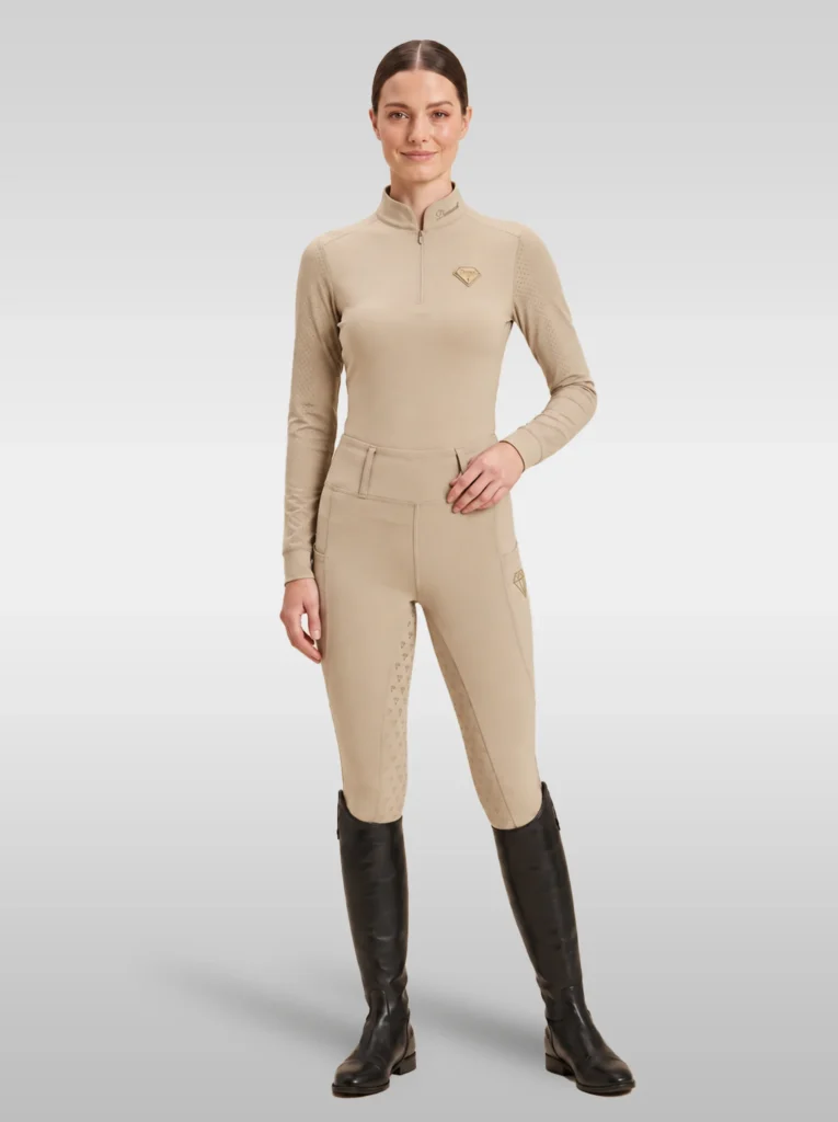 Rider wearing the beige Prestige long sleeve base layer with matching beige riding leggings and tall riding boots, full body