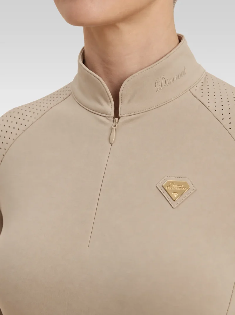 Close-up of the beige Prestige long sleeve base layer: Diamont signature on the collar, quarter-zip, perforated shoulder panel and gold metal badge