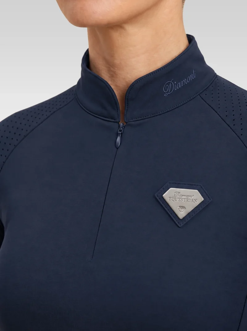 Close-up of the navy Prestige long sleeve base layer: Diamont signature on the collar, quarter-zip, perforated shoulder panel and silver metal badge in a navy leather frame