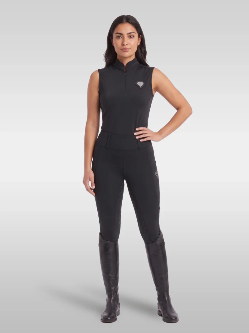 Rider wearing the black Prestige sleeveless base layer with matching black riding leggings and tall riding boots, full body
