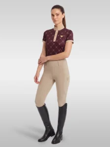 Rider wearing the burgundy Diamont base layer with beige riding breeches and tall black riding boots, full body