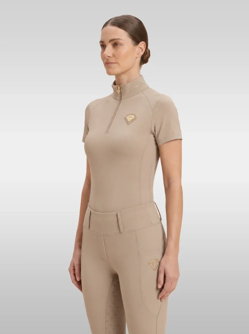 Beige Prestige base layer by Diamont Equestrian with gold quarter-zip and gold metal diamond badge on the chest, front three-quarter view