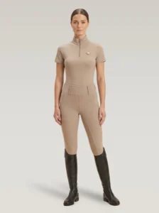Rider wearing the beige Prestige base layer with matching beige riding leggings and tall riding boots, full body