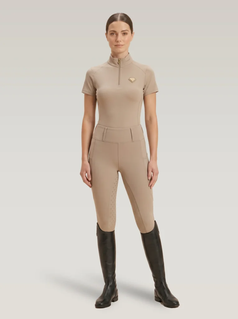 Rider wearing the beige Prestige base layer with matching beige riding leggings and tall riding boots, full body