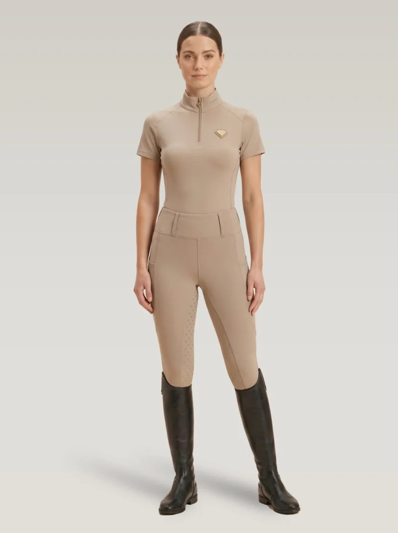 Rider wearing the beige Prestige base layer with matching beige riding leggings and tall riding boots, full body