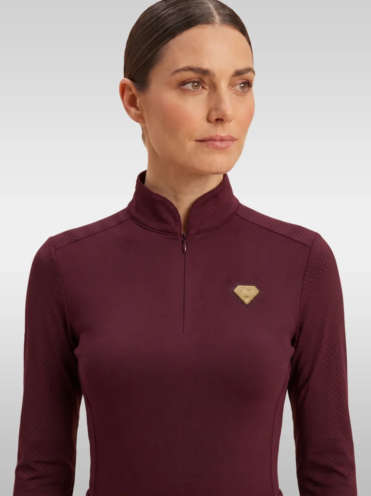 Front view of the burgundy Prestige long sleeve base layer by Diamont Equestrian with high collar, zip and gold diamond badge