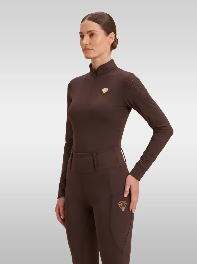 Chocolate brown Prestige long sleeve base layer by Diamont Equestrian with quarter-zip, perforated shoulders and gold metal diamond badge, front three-quarter view