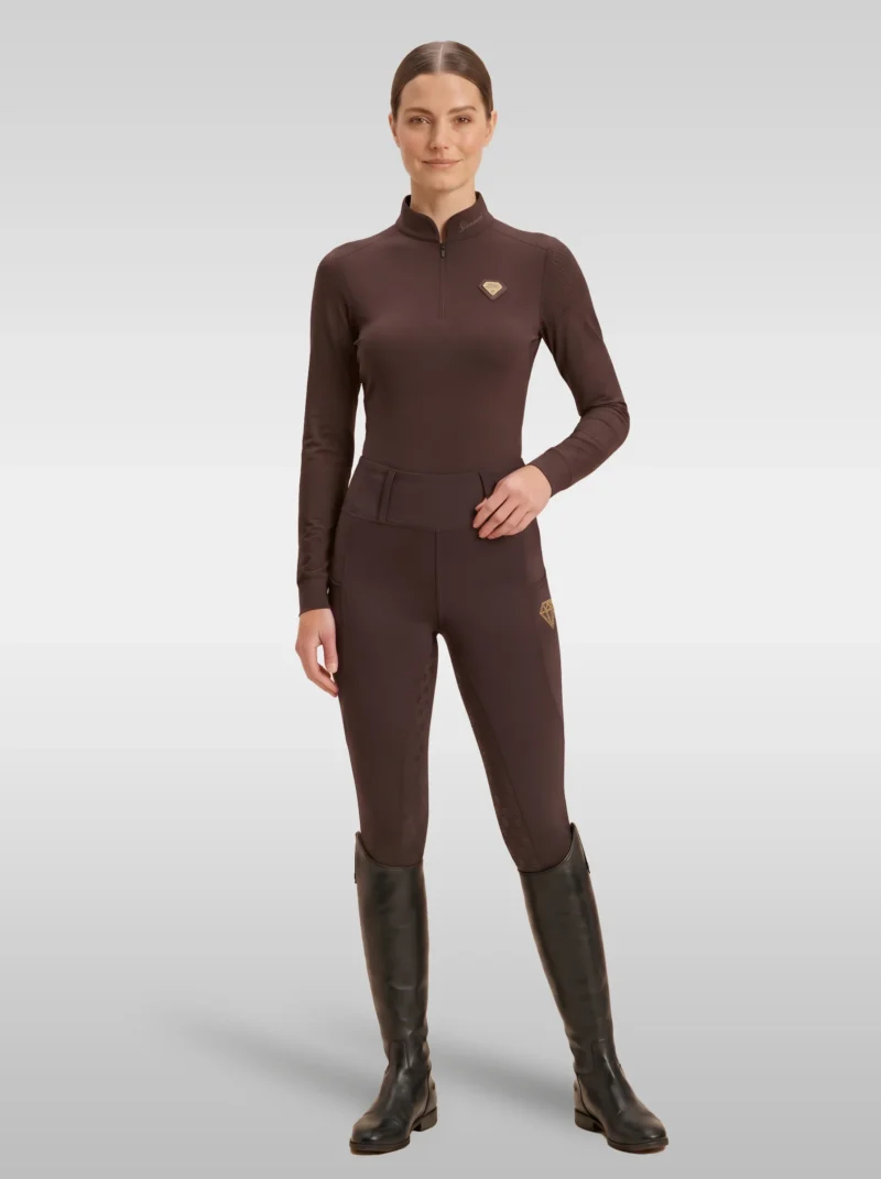 Rider wearing the chocolate brown Prestige long sleeve base layer with matching chocolate riding leggings and tall riding boots, full body