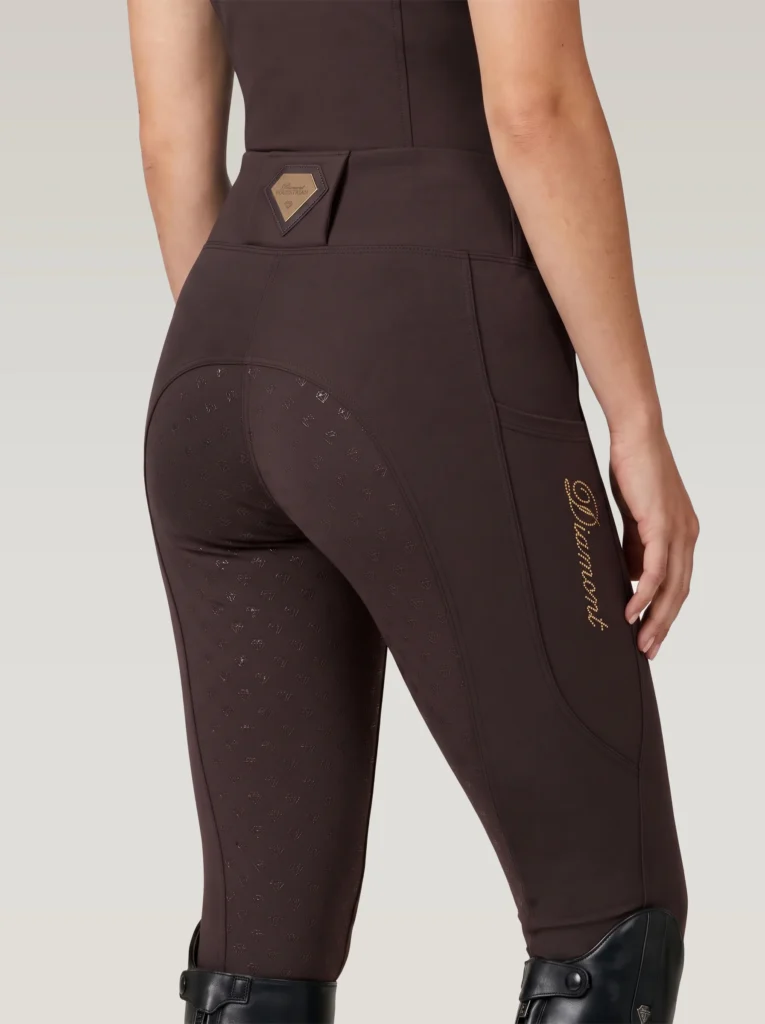 Back three-quarter view of chocolate brown equestrian leggings with full-seat diamond grip, waistband badge and gold Diamont script