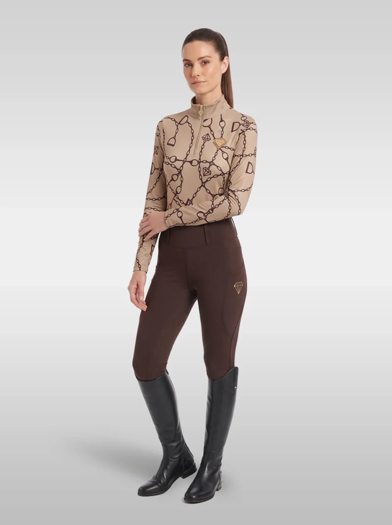 Rider wearing the beige Signature long sleeve base layer with chocolate brown riding leggings and tall black riding boots, full body