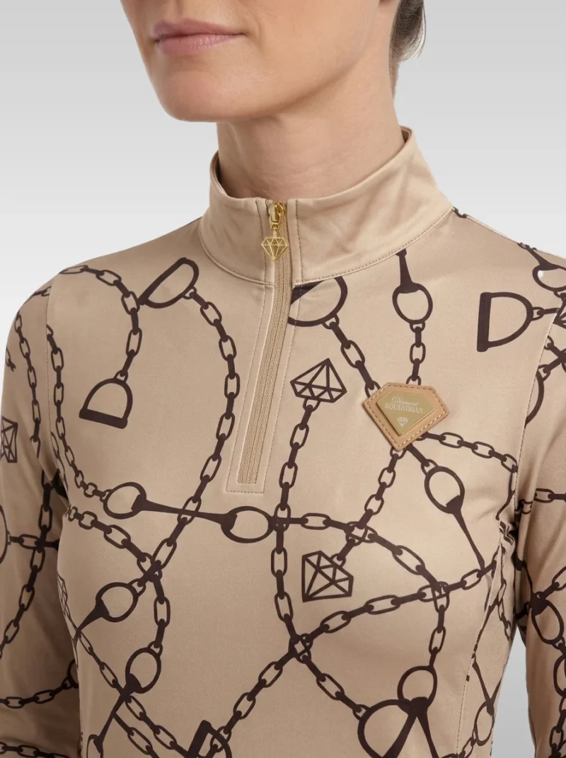 Close-up of the beige Signature long sleeve base layer: stand-up collar, gold quarter-zip, chain and stirrup print and gold metal diamond badge